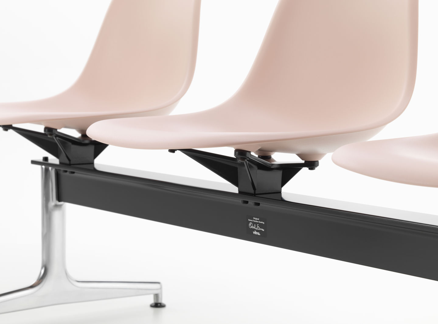 Detailaufnahme: Eames Plastic Side Chair RE auf Traverse von Vitra, Sitzschalen in zartem Rosa, modernes Design.