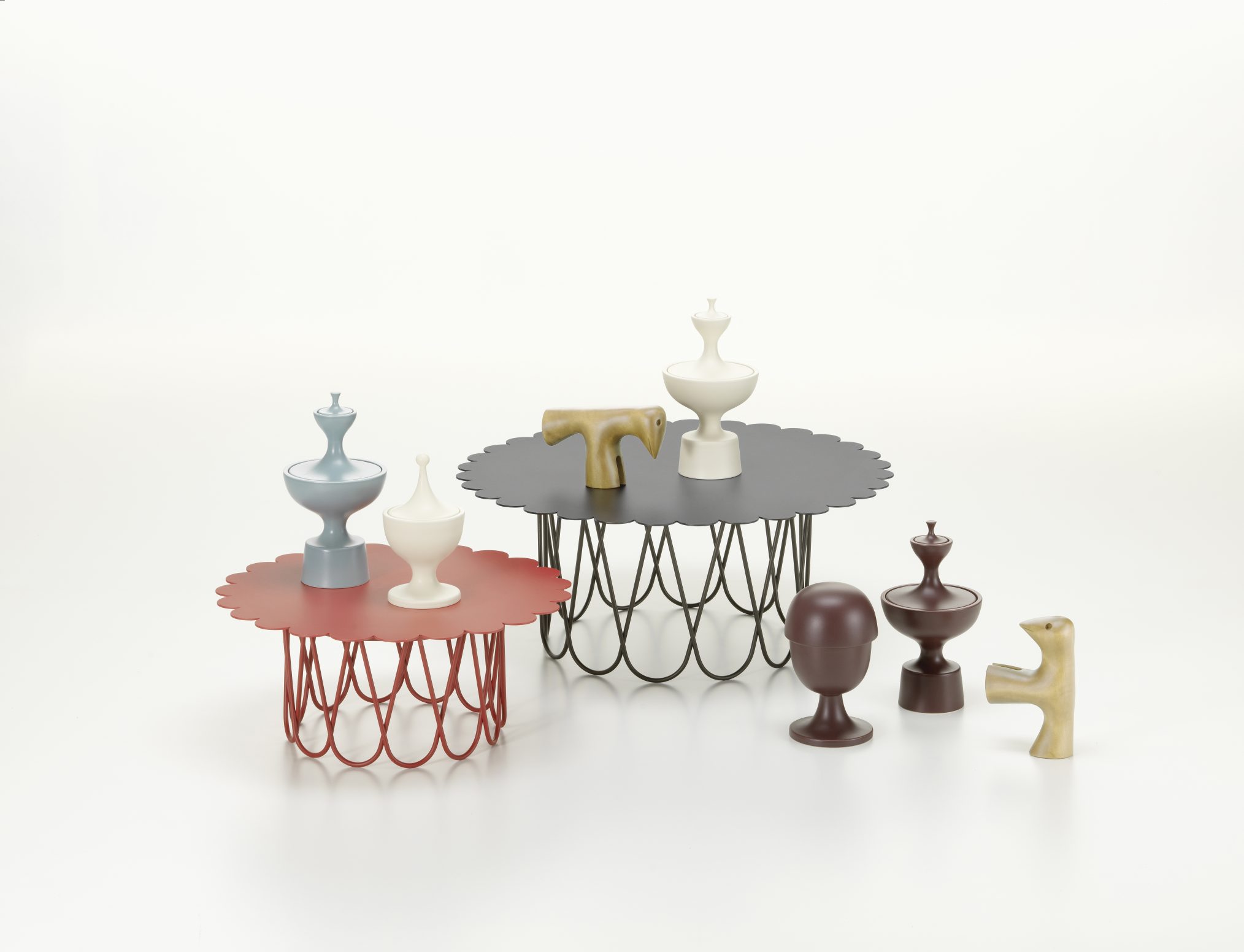 Vitra Flower Table Beistelltische in Rot und Schwarz mit dekorativen Objekten auf weißem Hintergrund.