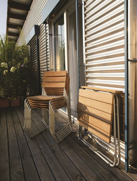 Weishäupl Balcony Klapptisch aus Teak mit Edelstahlgestell, platzsparend zusammengeklappt auf einem Balkon.