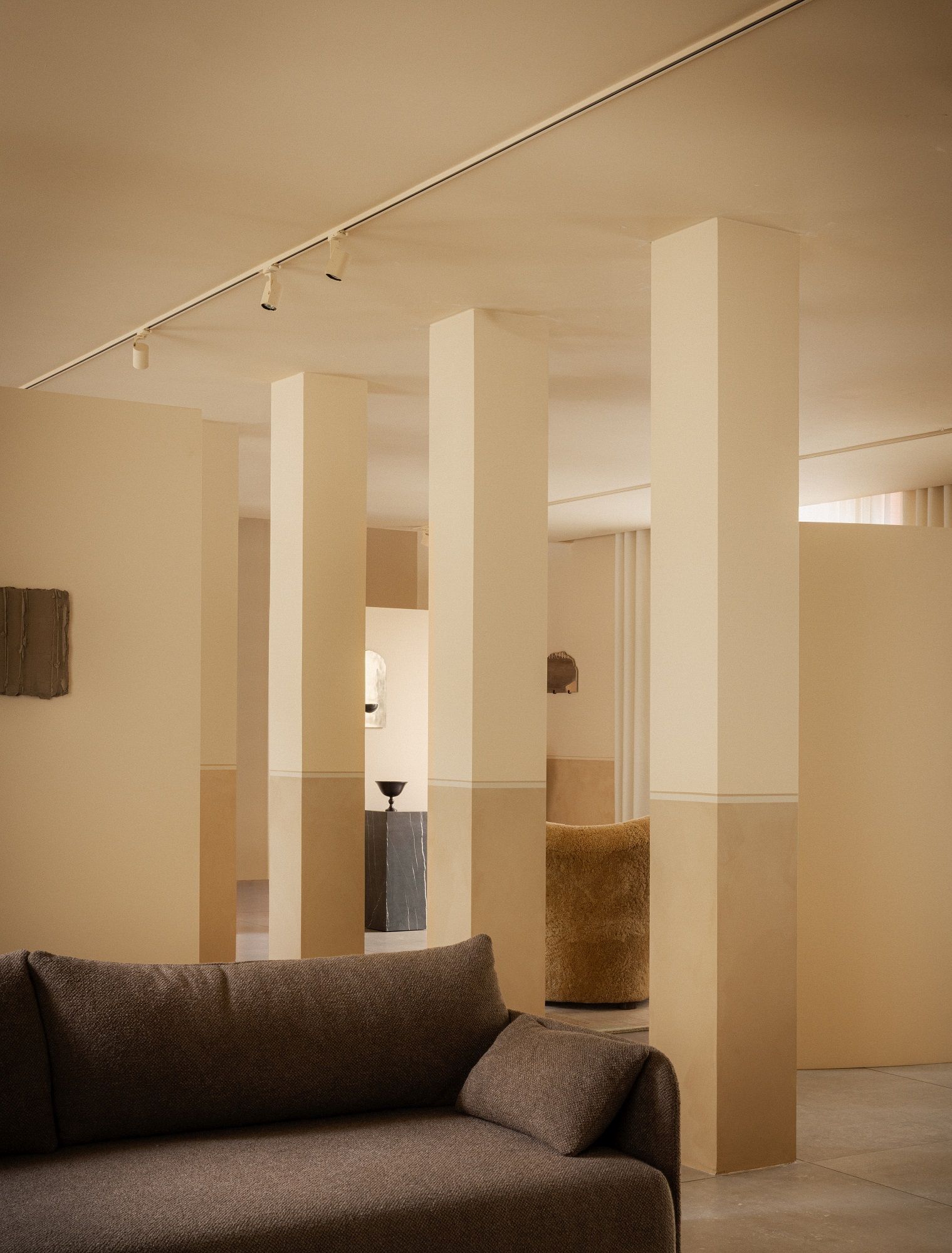 Nahaufnahme des braunen Audo Copenhagen Offset Sofas mit drei Sitzen in minimalistischem, beigem Interieur.