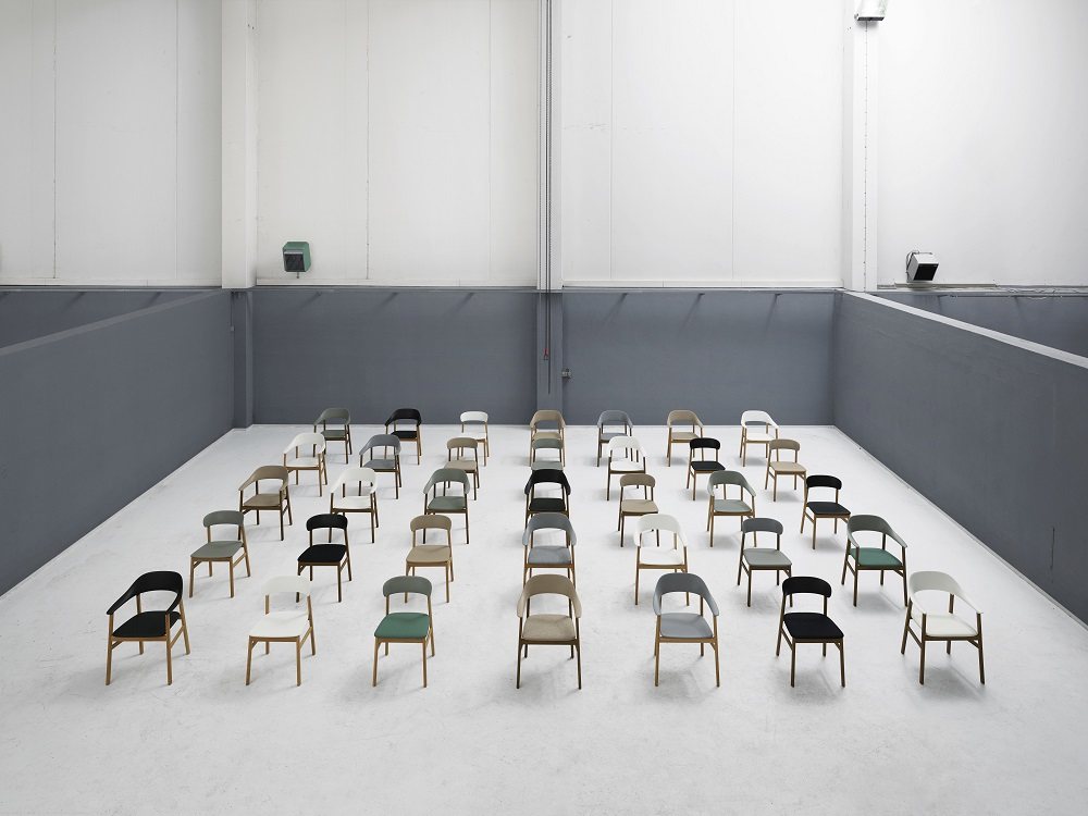 Viele Herit Stühle von Normann Copenhagen in verschiedenen Farben in einem minimalistischen Raum.