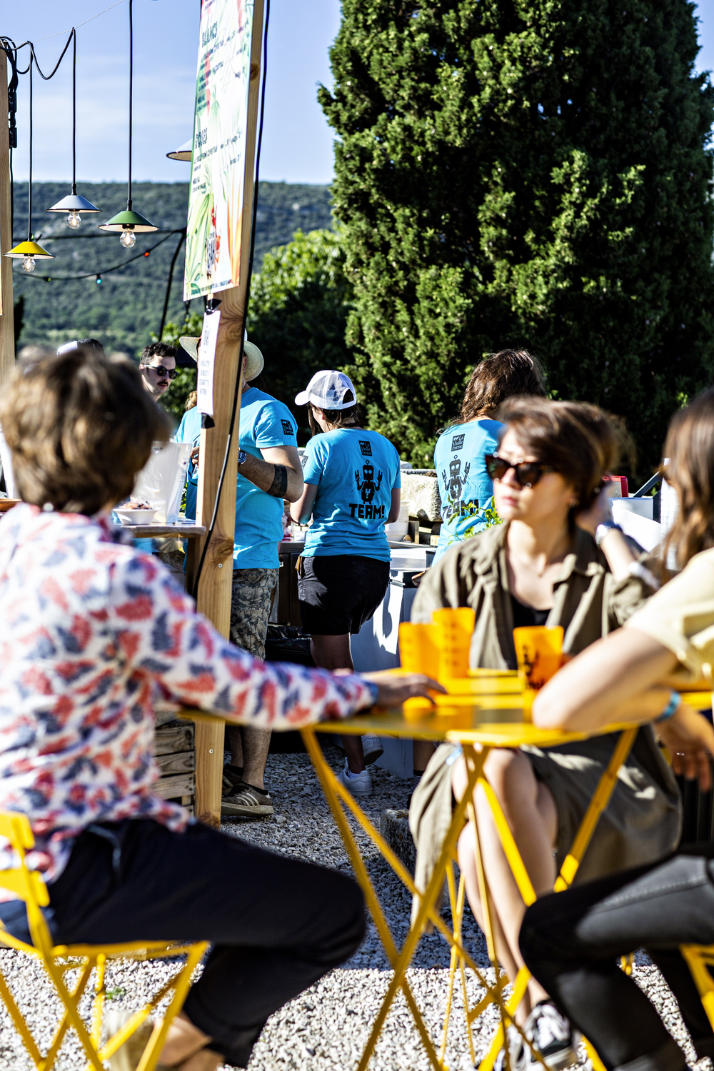 Gelber Bistro Gartenstuhl von Fermob, ideal für den Außenbereich, mit Menschen an einem sonnigen Tag.