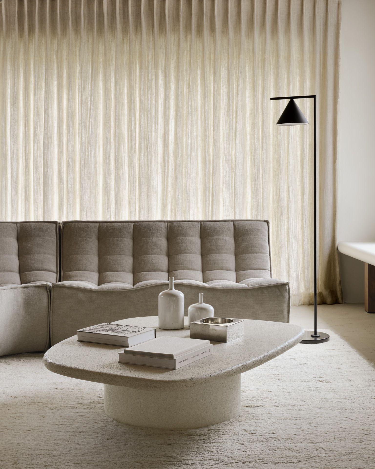 Elements Couchtisch von Ethnicraft: Kieselform Microcement Tisch in modernem Wohnzimmer mit Sofa und Teppich.