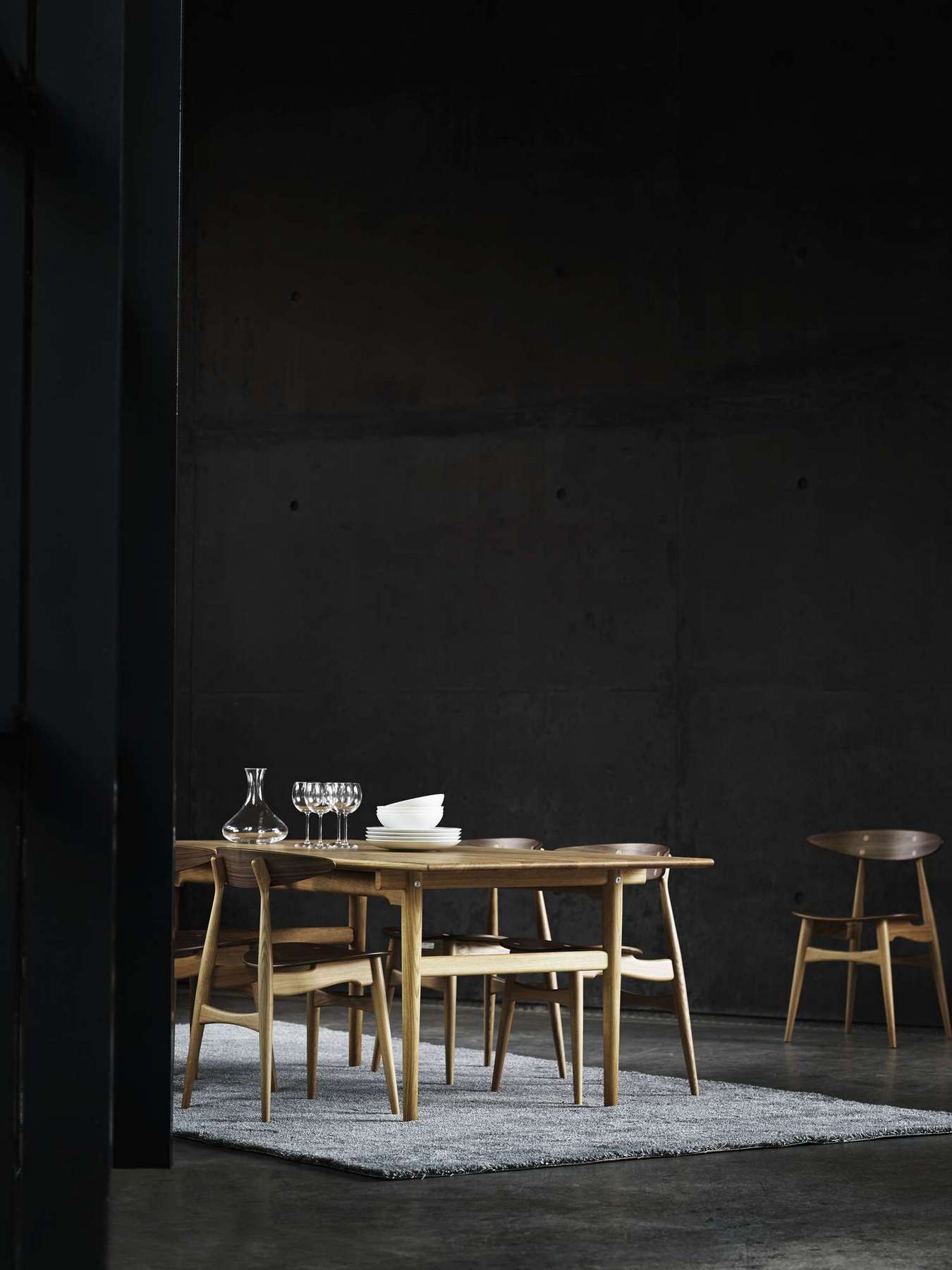 CH327 Tisch von Carl Hansen mit Stühlen, Karaffe, Gläsern und Geschirr auf einem Teppich.