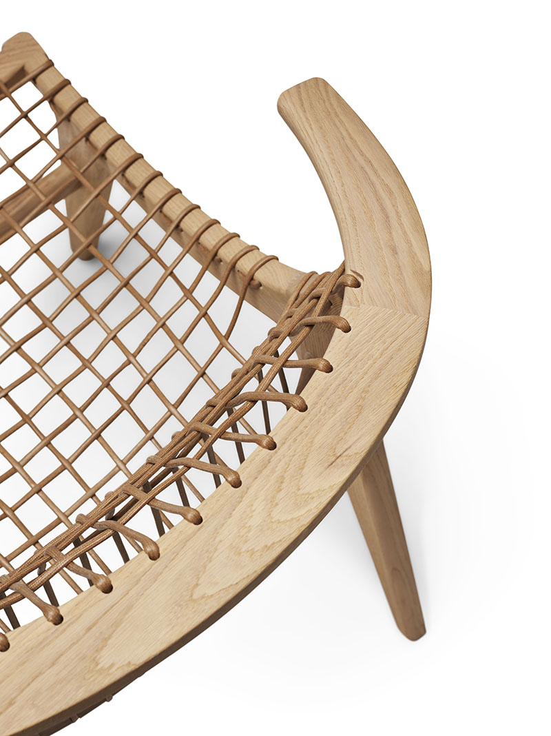 Detailaufnahme: Klismos Lounge Sessel mit Holzrahmen und geflochtener Sitzfläche. Designmöbel für Wohnzimmer und Lounge.