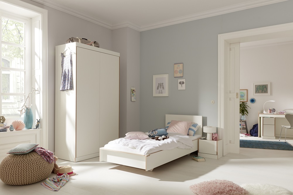 Heller Raum mit Flai Kleiderschrank (Müller Möbelwerkstätten) und weißem Bett für Kinderzimmer.