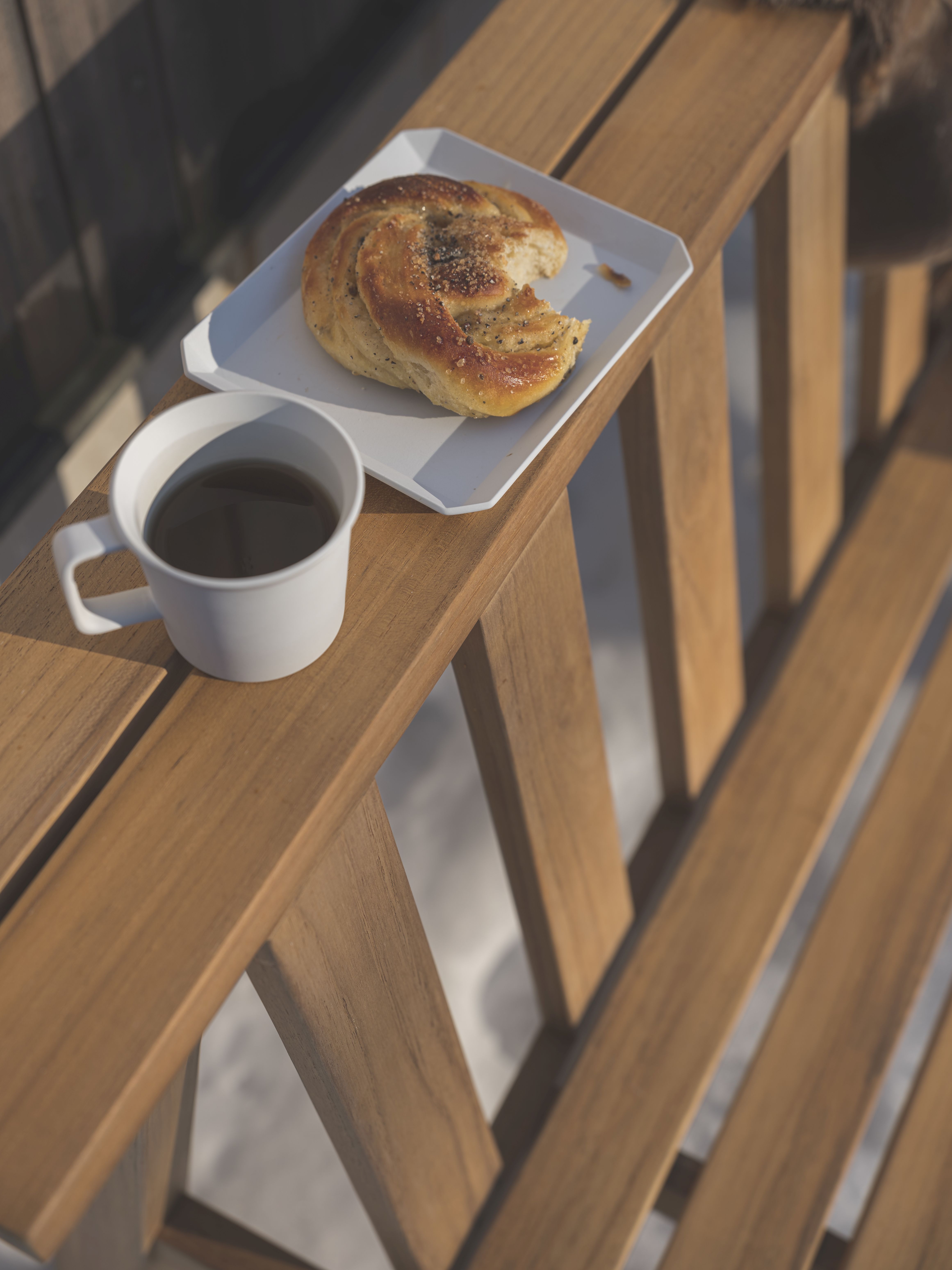 Cadence Bank Teakholz Gartenbank von Fritz Hansen mit Kaffee und Gebäck im Freien.