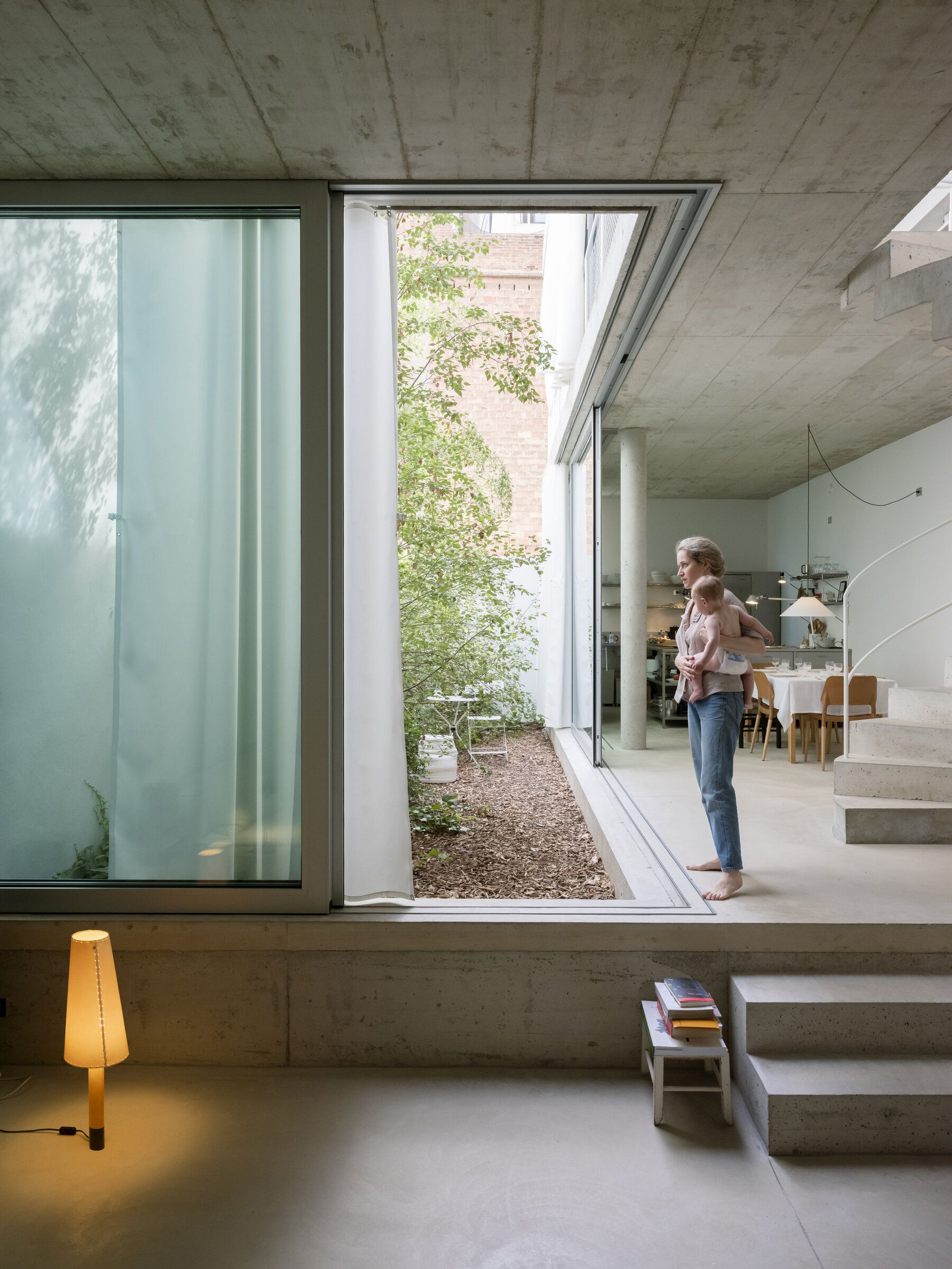 Basica Tischleuchte von Santa & Cole im modernen Wohnzimmer mit Frau und Baby, warmes Licht.