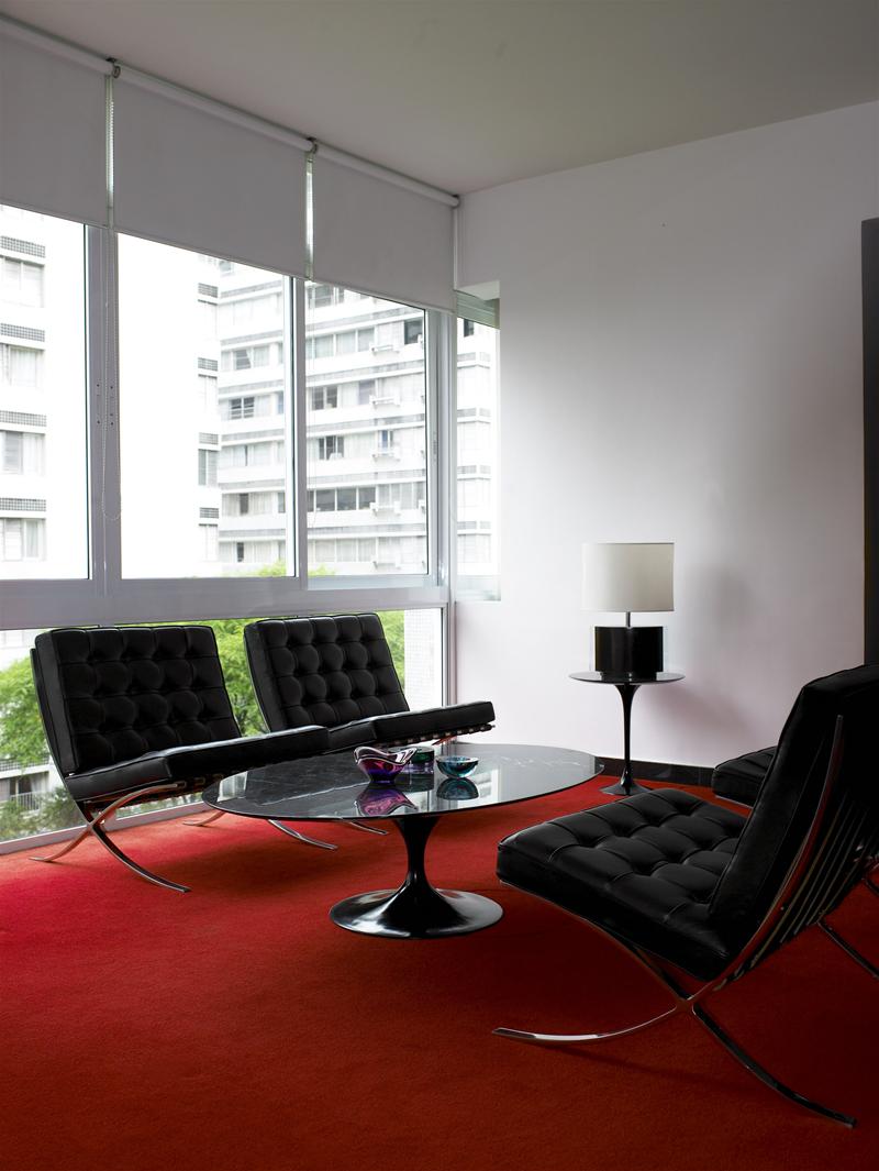 Barcelona Sessel von Knoll International mit schwarzem Leder, verchromtem Gestell und passendem Couchtisch auf rotem Teppich.