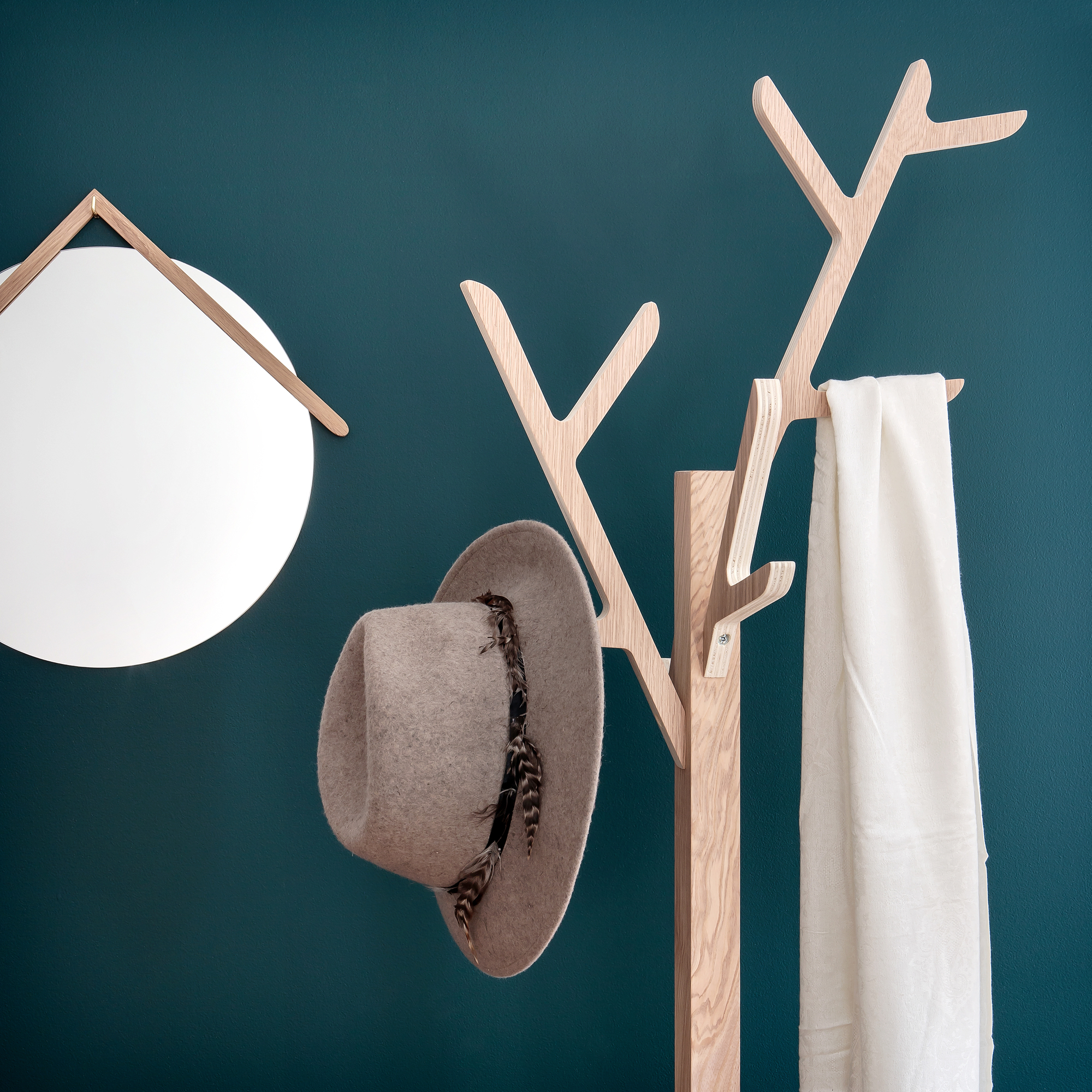Hartô Ambroise Garderobenständer aus Eiche mit Hut, Schal und Spiegel an dunkelblauer Wand.