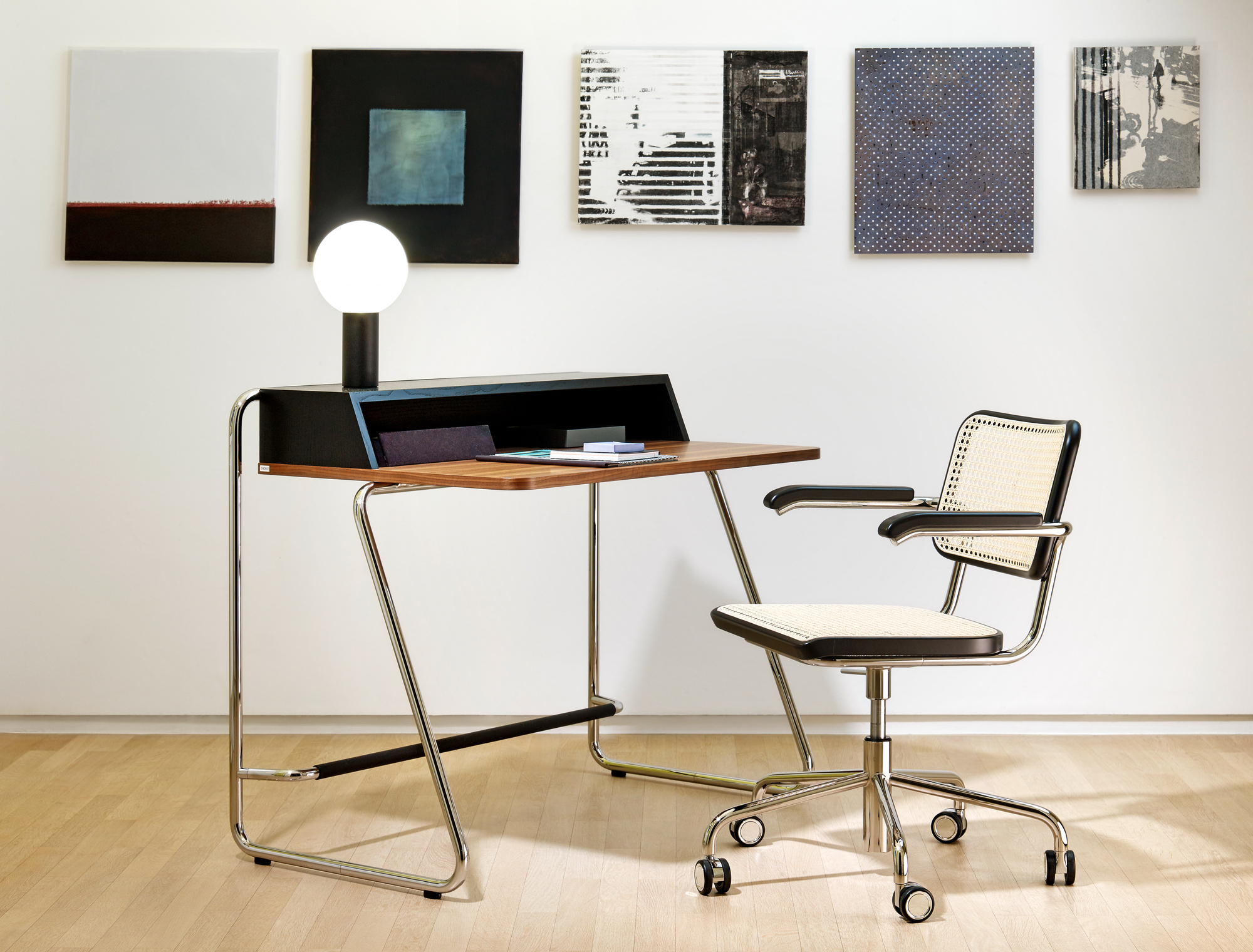S 1200 Thonet Sekretär mit Stahlrohrgestell und passendem Bürostuhl mit Wiener Geflecht vor Kunstwerken.