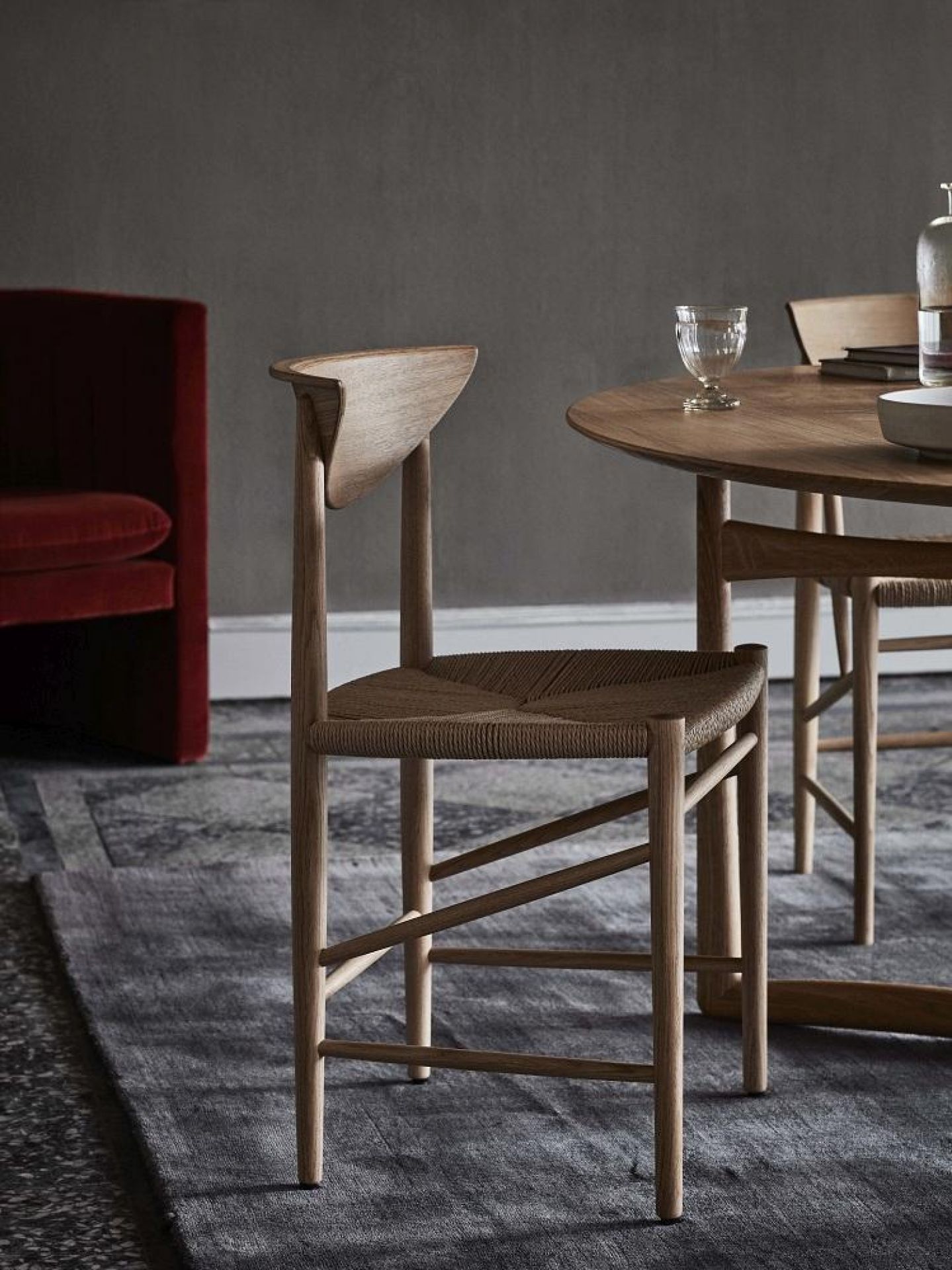 Holzstuhl mit geflochtener Sitzfläche und abgerundeter Rückenlehne am Esstisch, skandinavisches Design.