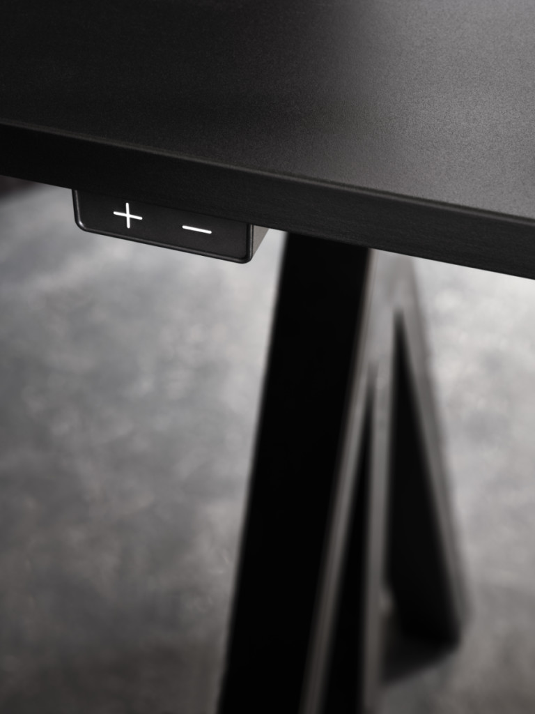 Detailaufnahme: Works Schreibtisch von String Furniture mit Bedienelementen zur Höhenverstellung in Schwarz.