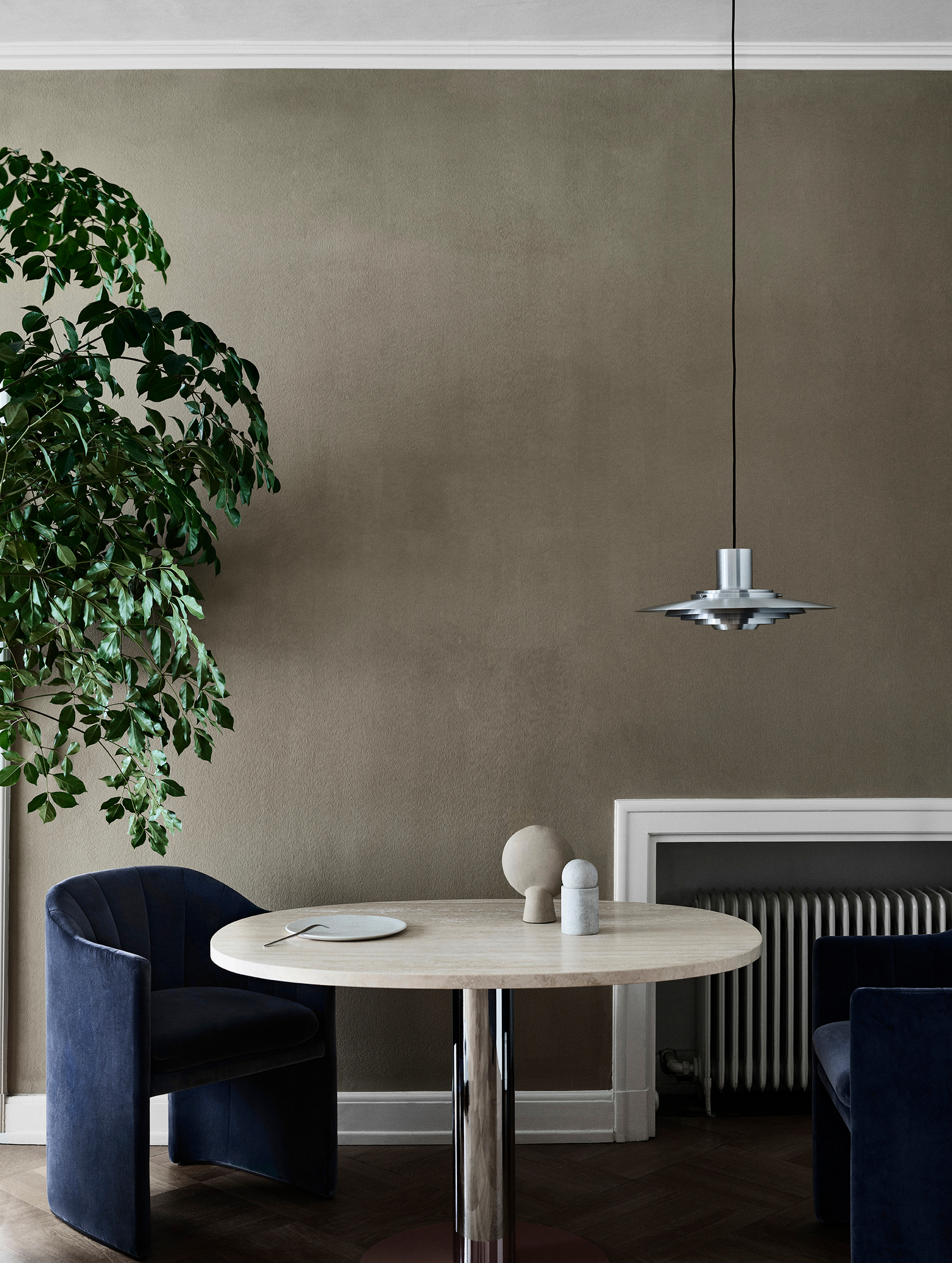 Esszimmer Interieur mit AndTradition P376 Pendelleuchte über rundem Tisch und blauen Samtstühlen, stilvolle Beleuchtung und Möbel.