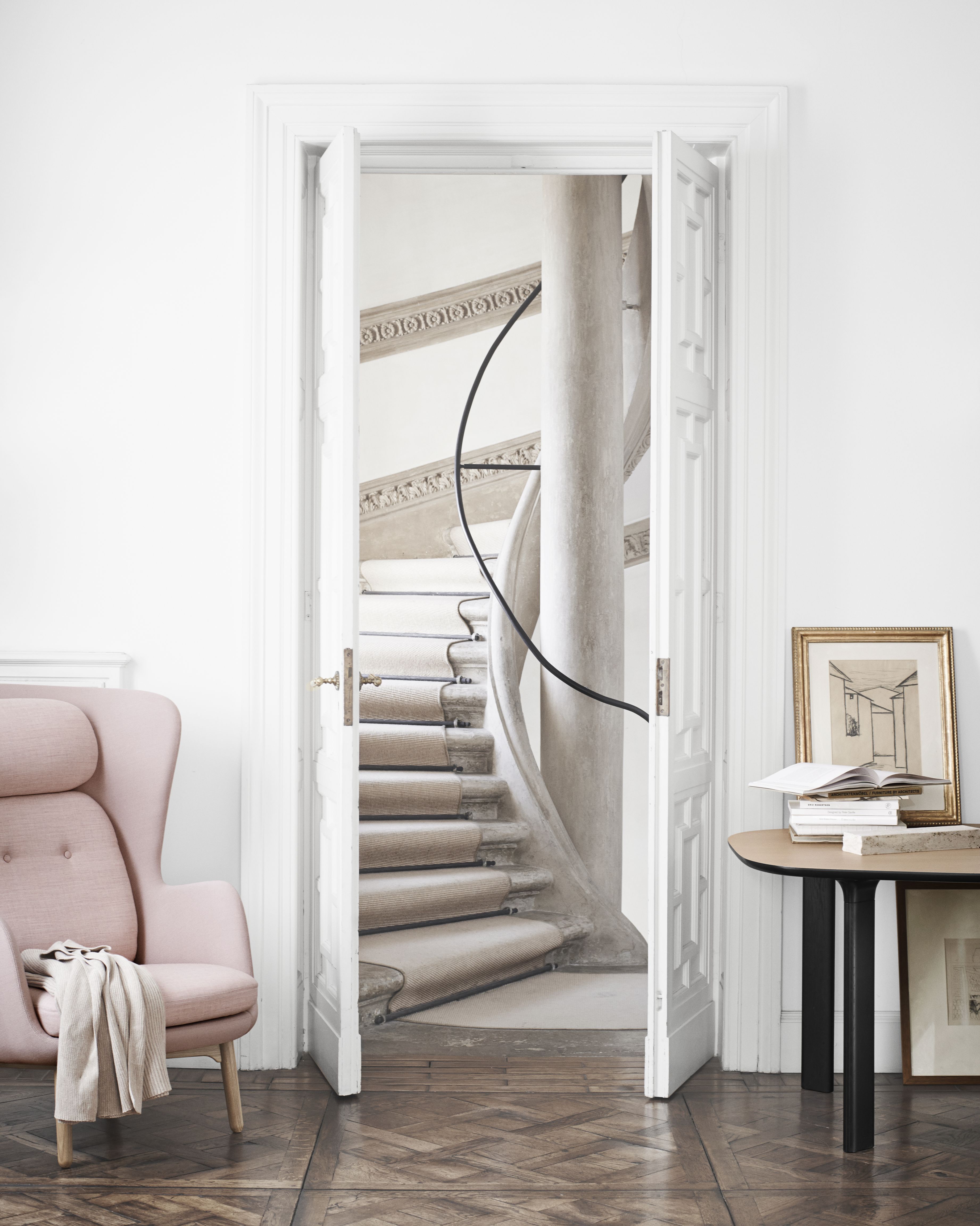Rosa Ro Sessel von Fritz Hansen in stilvollem Interieur mit Treppe und Holzboden.