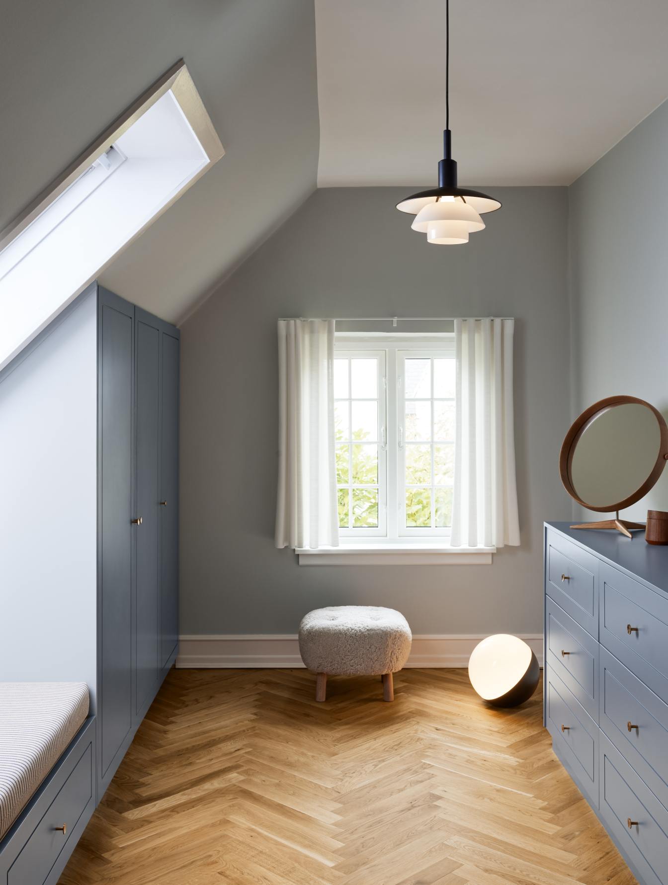 Helle, moderne Dachgeschoss-Einrichtung mit PH Pendelleuchte von Louis Poulsen und blauen Möbeln.