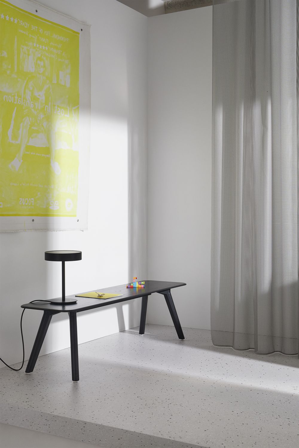MEYER Bank Large Out: Schwarzer Design Tisch mit Lampe und bunten Stiften im minimalistischen Raum.