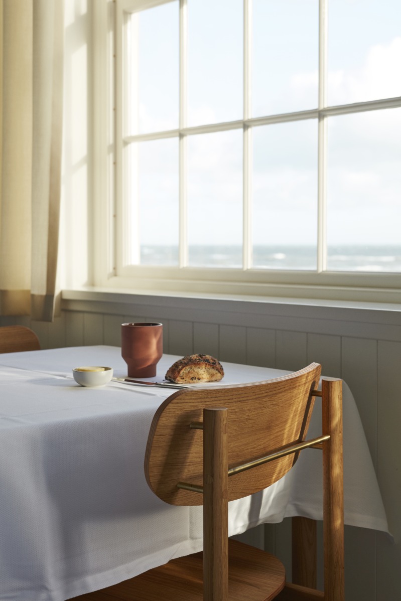 Vester Chair Stuhl von Skagerak by Fritz Hansen am Esstisch mit Meerblick.
