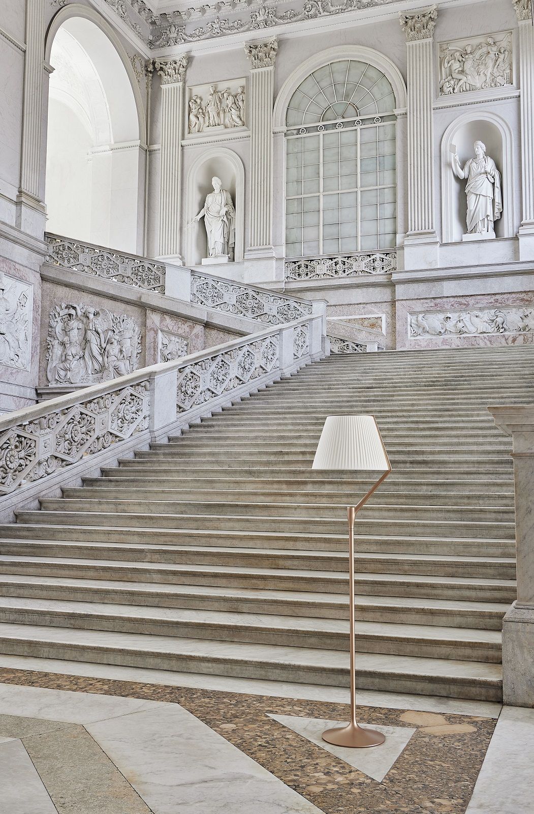 Angelo Stone Stehleuchte von Kartell, moderne Bodenleuchte mit plissiertem Lampenschirm vor klassischer Treppe.