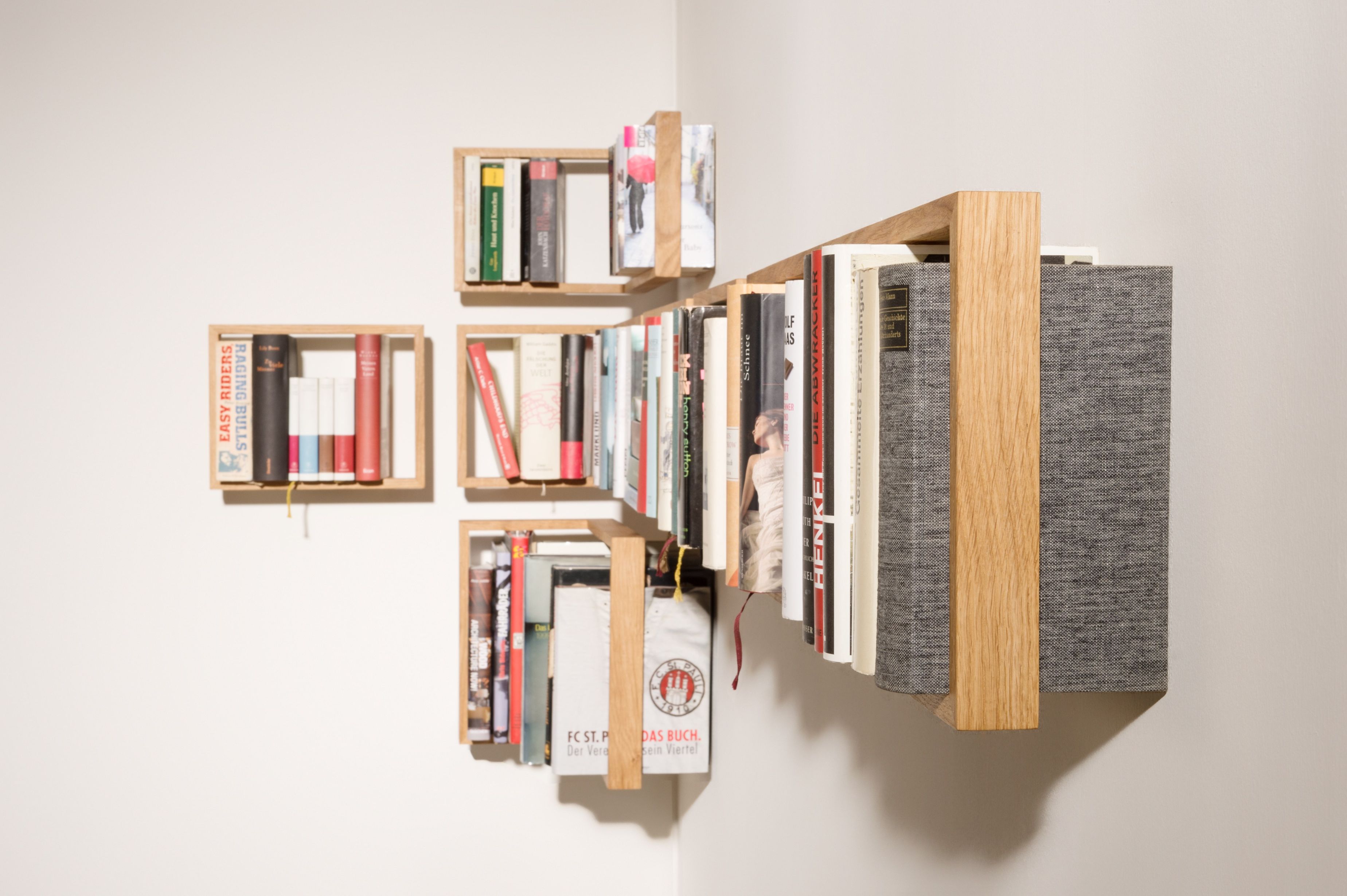 Detailaufnahme des Regal b Eiche das kleine b EINZELSTÜCK, ein modernes Bücherregal aus hellem Holz an einer weißen Wand.