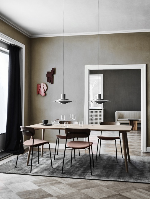 Esszimmer mit AndTradition Pavilion AV3 Stühlen und Holztisch auf einem grauen Teppich.