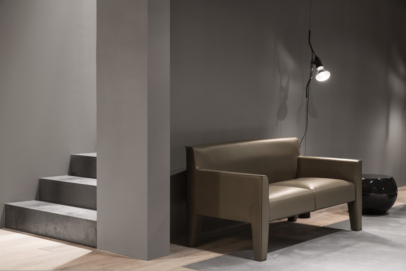 Innenaufnahme mit Flos Parentesi D Lampe, weiß, neben modernem Sofa und Treppe.