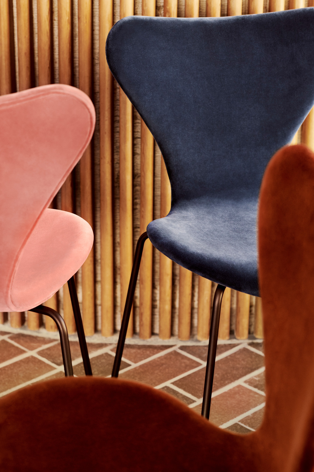 Nahaufnahme von drei Series 7 Stühlen mit Vollpolster in Samt, Fritz Hansen.