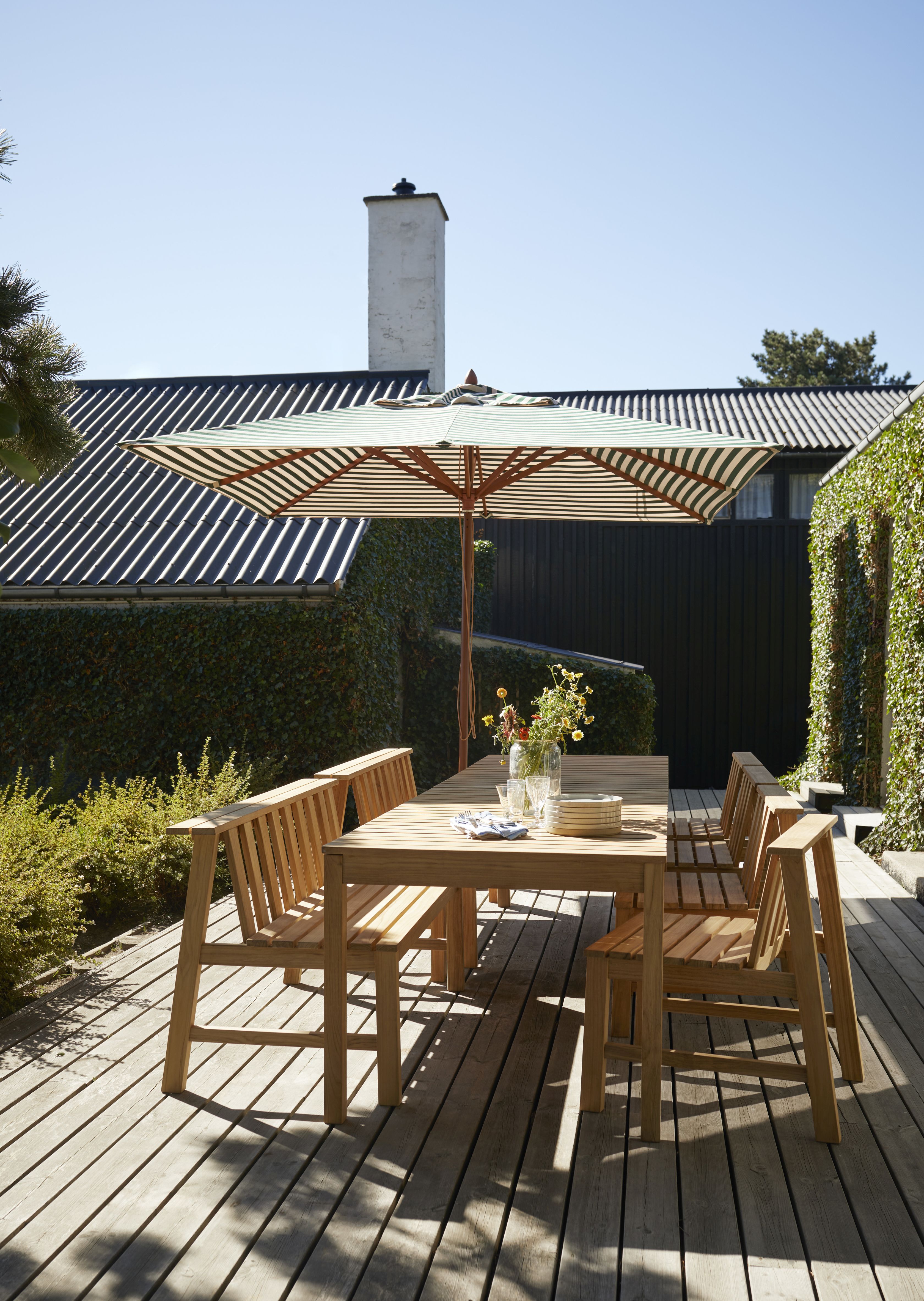 Cadence Bank Teak Gartengarnitur von Skagerak by Fritz Hansen mit Tisch, Stühlen und Sonnenschirm.