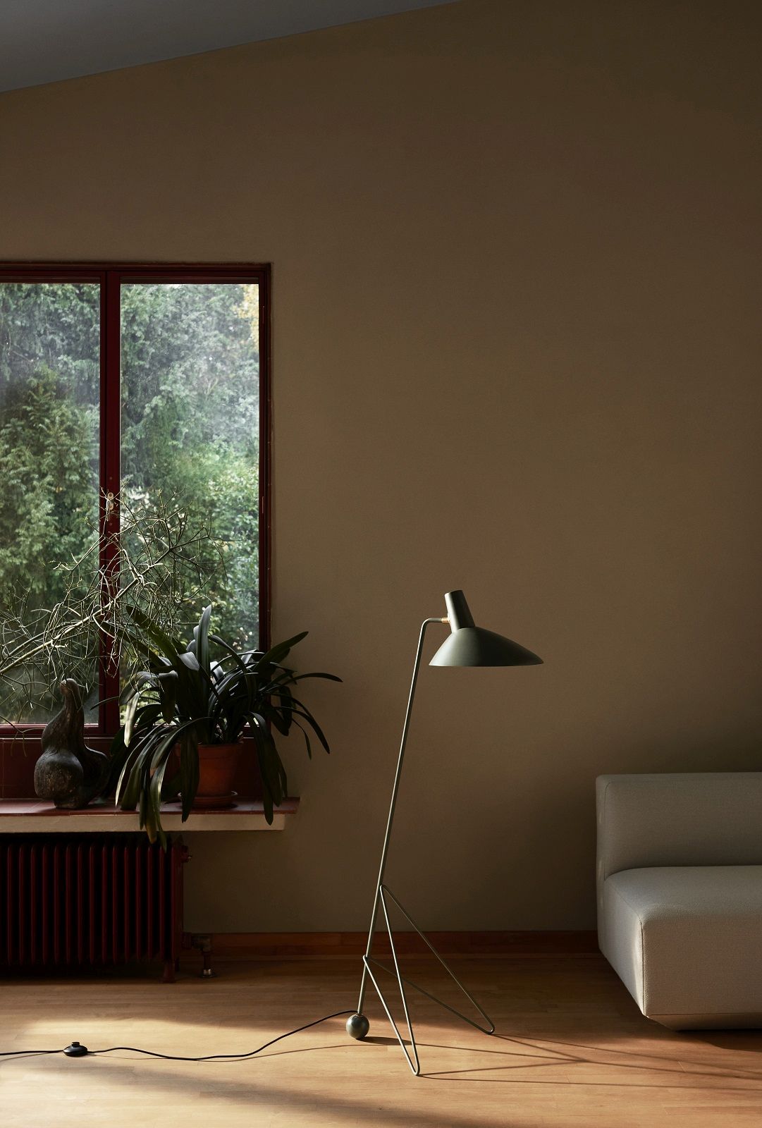 AndTradition Tripod HM8 Stehleuchte in Grün, modernes Design im Wohnzimmer mit Fenster und Pflanze.