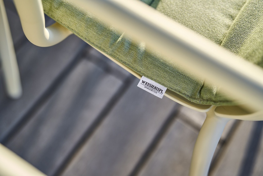 Detailaufnahme vom Weishäupl Vapio Stuhl Outdoor mit grünem Sitzkissen und dem Markenlogo.