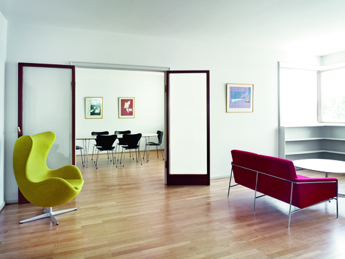 Rotes Fritz Hansen Serie 3300 Sofa und gelber Sessel in modernem, hellem Wohnzimmer mit Holzboden.