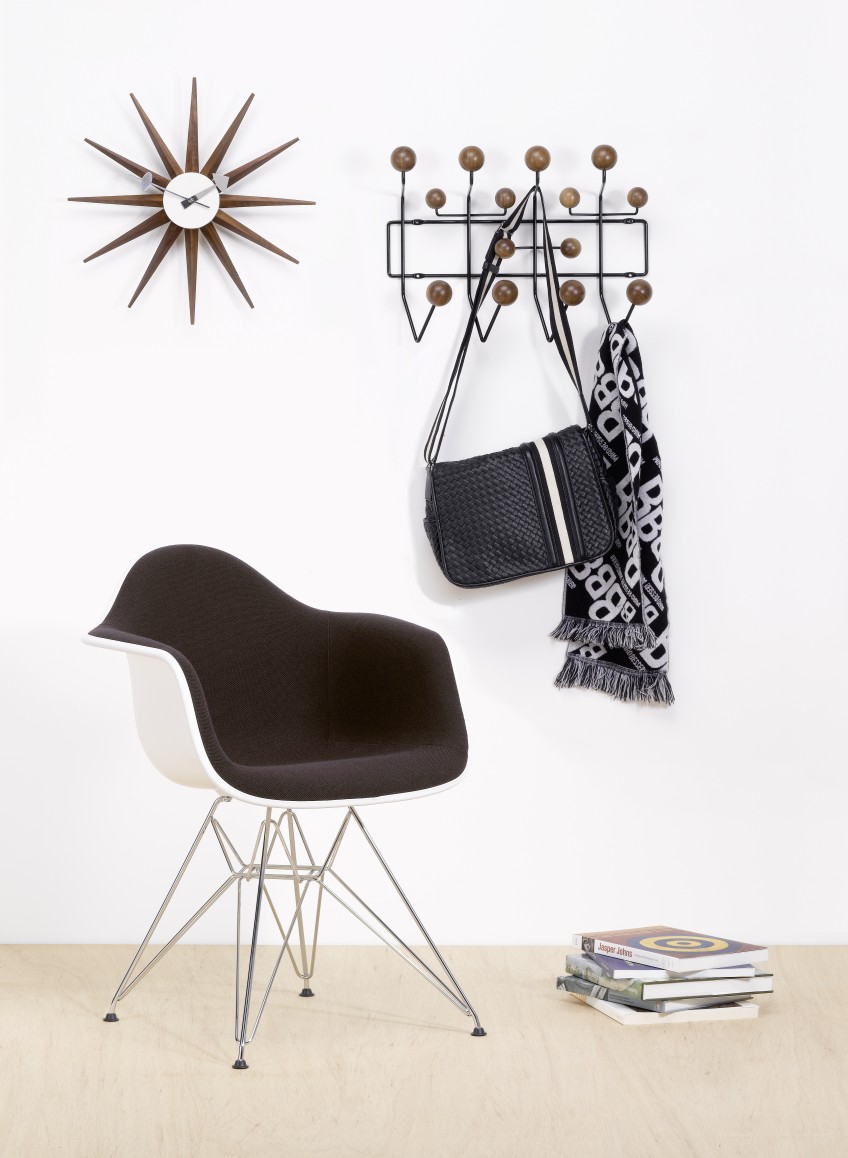 Sunburst Clock Wanduhr aus Nussbaumholz von Vitra über einem modernen Wohnzimmer mit Designermöbeln.