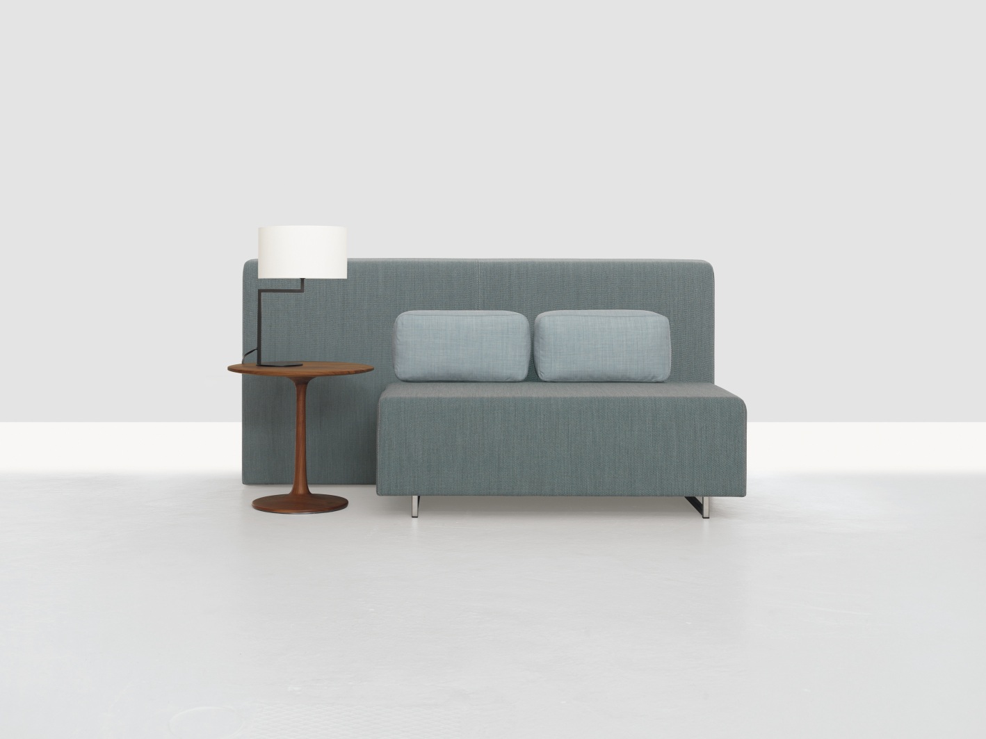 Turntable Couch Beistelltisch Zeitraum mit Lampe und zwei Kissen vor neutralem Hintergrund.