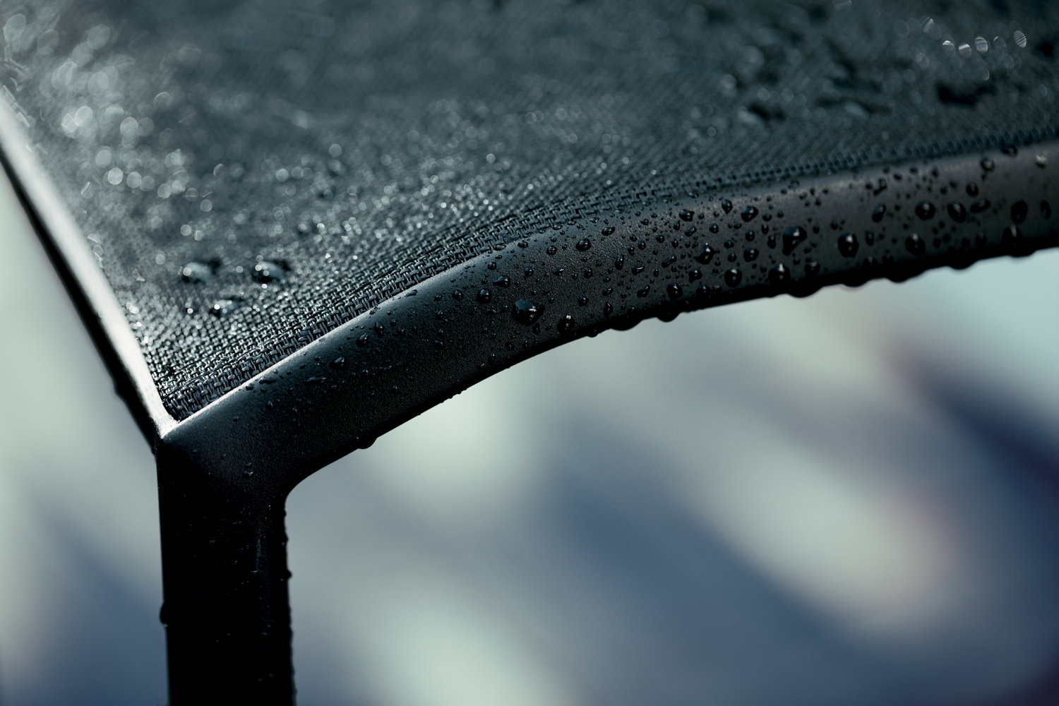 Detailaufnahme des schwarzen Cadiz Outdoor Stuhls von Fermob mit Wassertropfen auf der Sitzfläche.