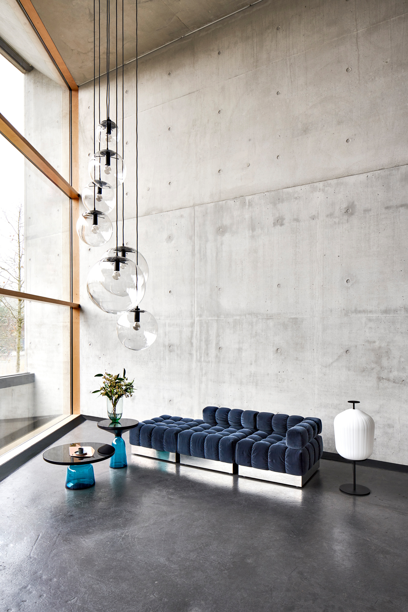Wohnzimmer mit blauem Sofa und zwei Bell Coffee Table Couchtischen mit bernsteinfarbener Platte.