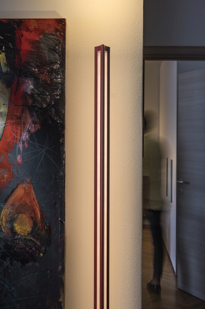 Chiaroscura Stehleuchte von Foscarini: Moderne, vertikale Bodenleuchte in Rot und Weiß neben einem Gemälde.