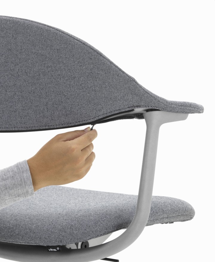 Detailaufnahme: Hand befestigt Bezug am grauen Mynt Bürodrehstuhl von Vitra, ergonomischer Arbeitsstuhl.