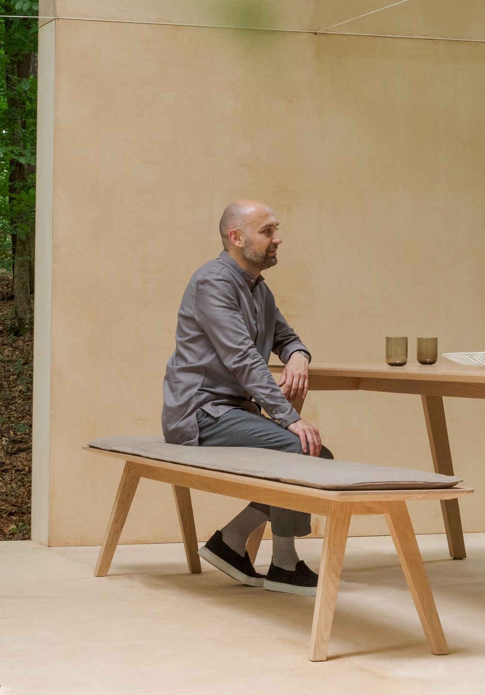 Mann sitzt am Monk Tisch von Prostoria, einem modernen Holztisch mit Bank.