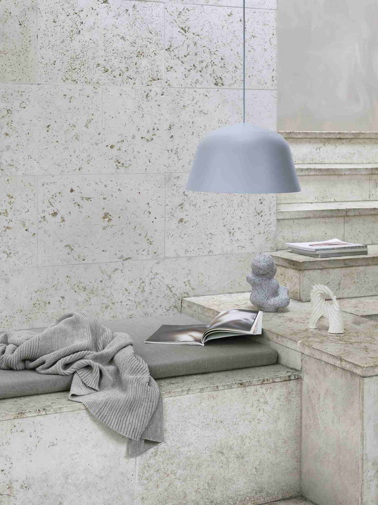 Helle Ambit Pendelleuchte von Muuto über einer Treppe mit Dekoration und Strickdecke.