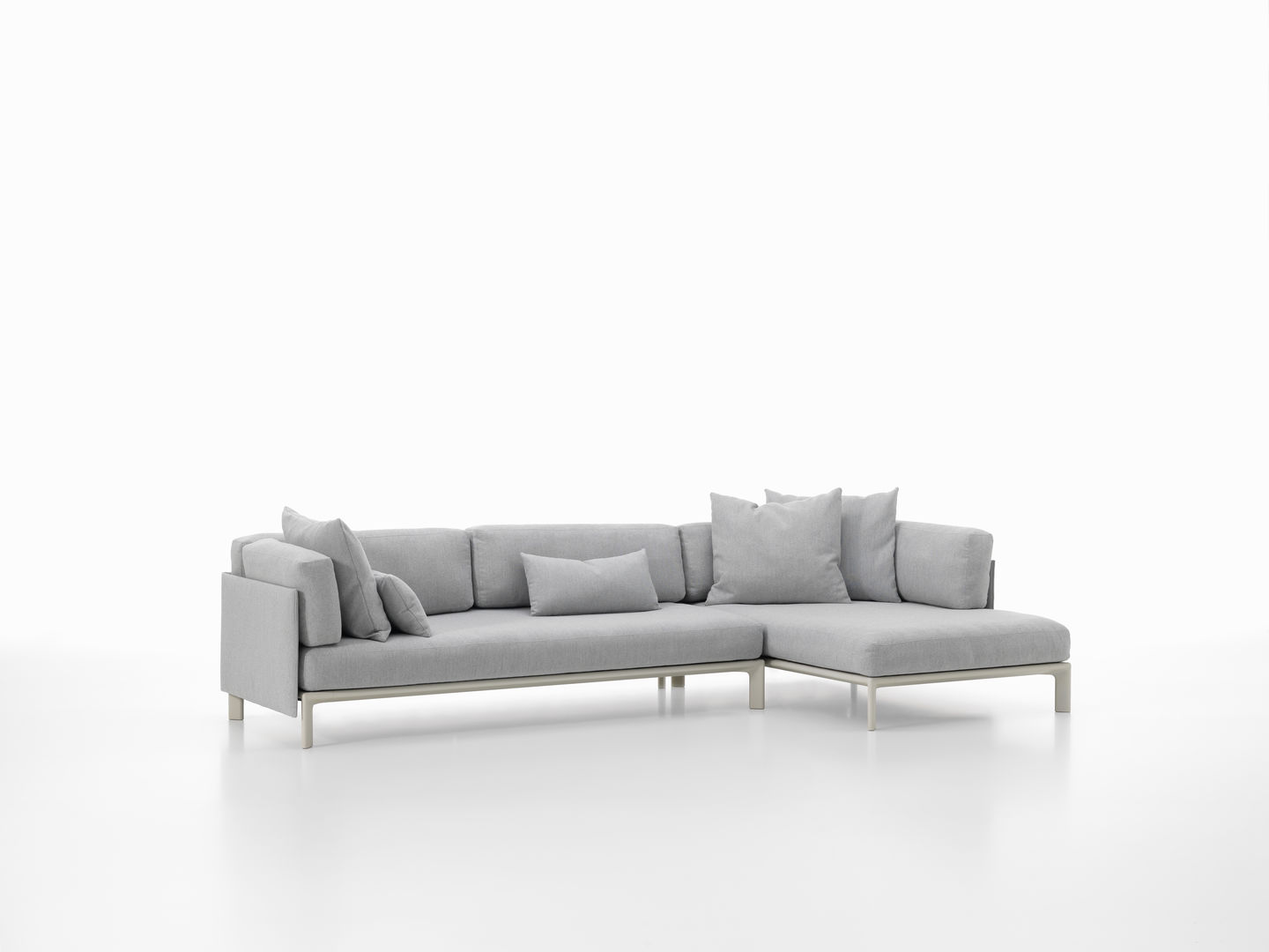 Vitra Anagram Sofa Plattform, graues Ecksofa mit Kissen und hellem Gestell, modernes Wohnzimmer Design.