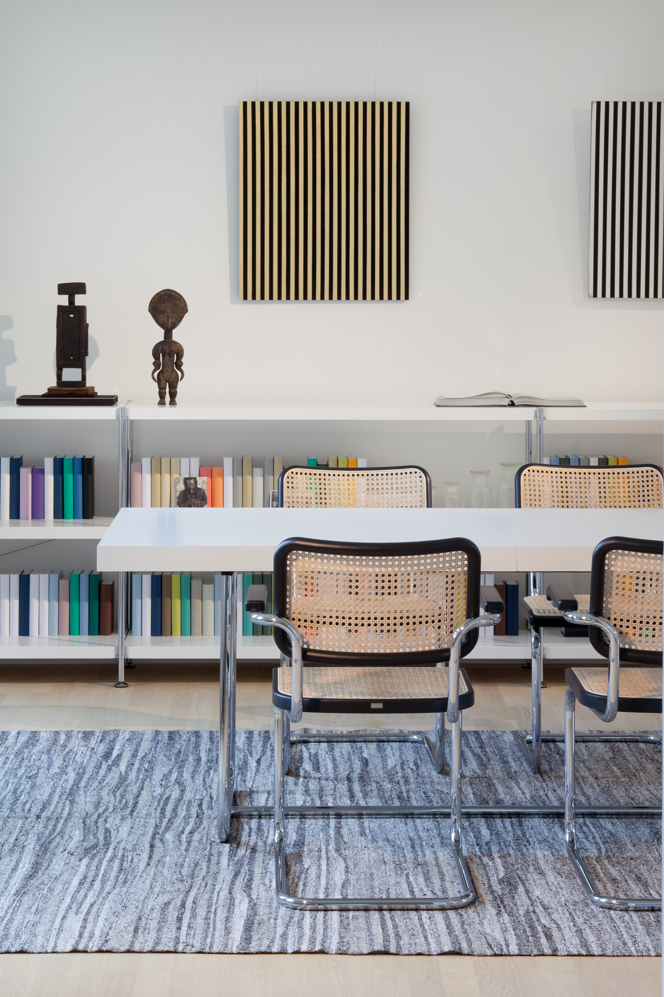 S 64 V Thonet Freischwinger Stühle aus Stahlrohr mit Wiener Geflecht vor Bücherregal und Teppich.