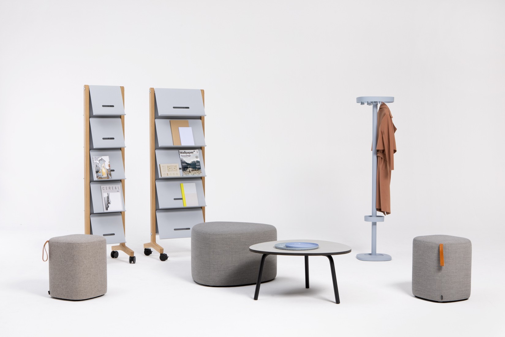 Cascando Pully Island Sitzelement Hocker in Grau, kombiniert mit Zeitschriftenregalen und Garderobenständer.