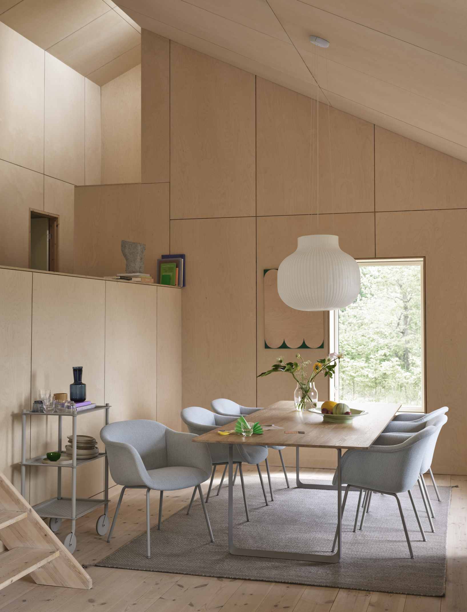 Muuto Fiber Armchair: Moderner Armlehnstuhl in Hellgrau am Esstisch in einem hellen, skandinavisch eingerichteten Raum.