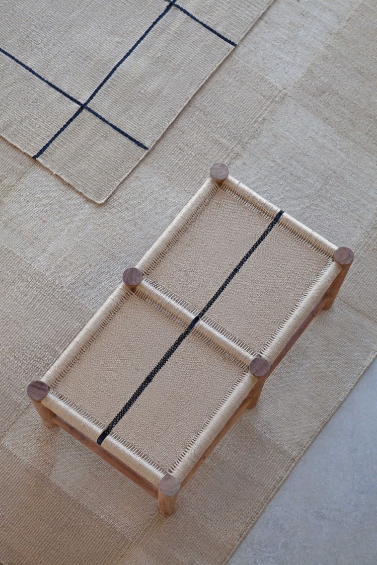 Roots Double Stool Bank Gan aus Holz und Naturfaser auf passendem Teppich, Vogelperspektive.