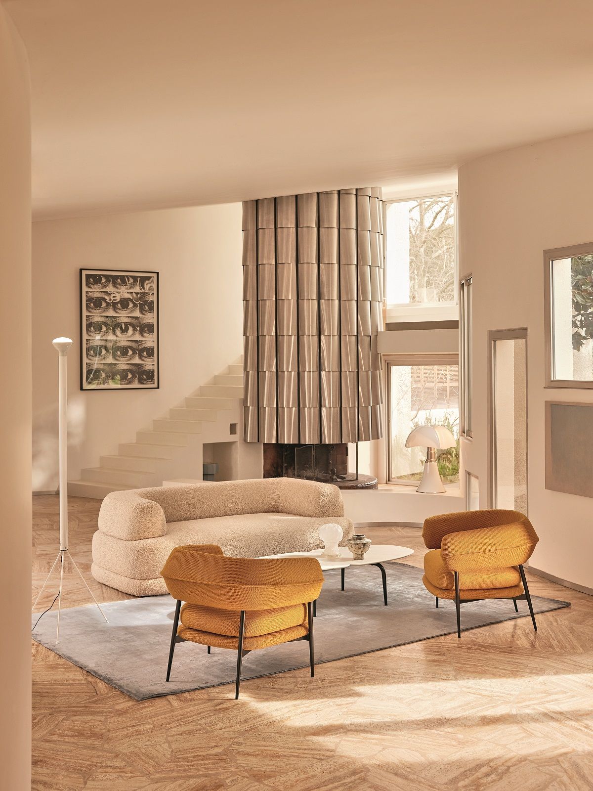 Wohnzimmer mit beigem Bumper Sofa von Zanotta und zwei gelben Sesseln auf einem Teppich.