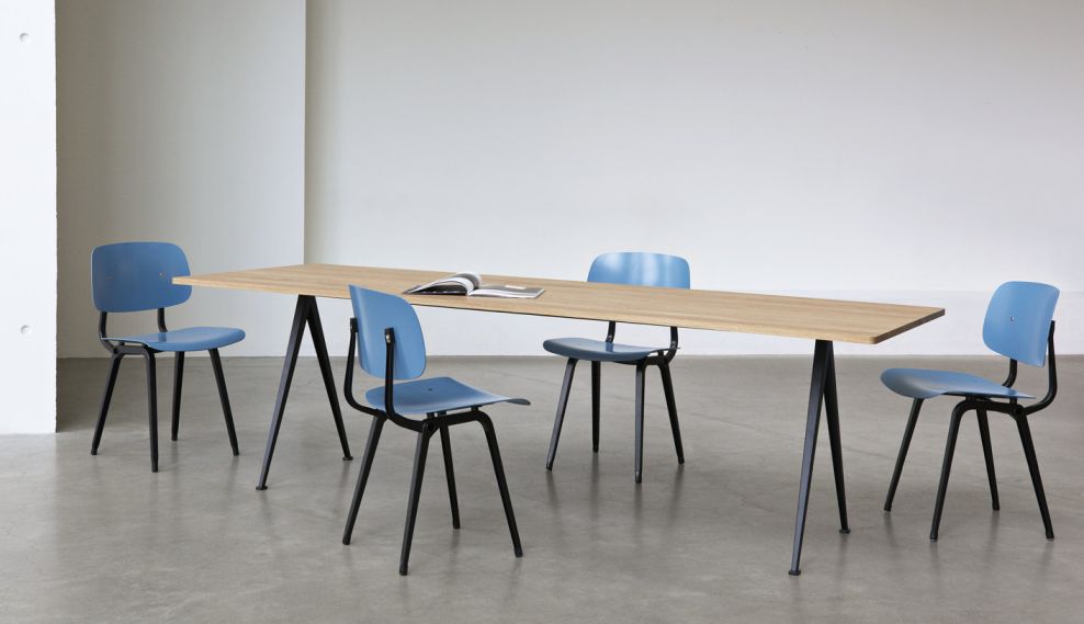 Vier blaue Hay Revolt Chair Stühle um einen Holztisch mit schwarzen Beinen, minimalistisches Design.