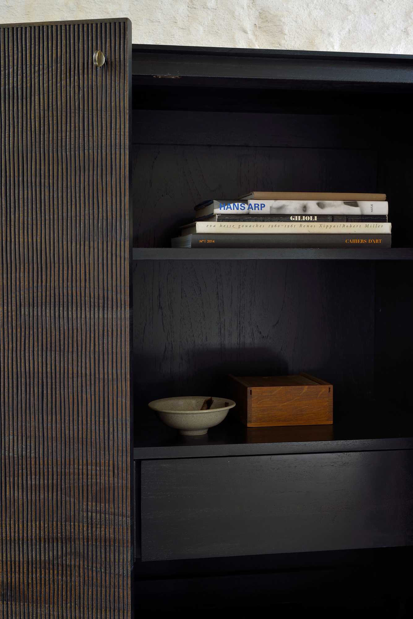 Ethnicraft Teak Grooves Schrank: Detailaufnahme des dunklen Holzschranks mit markanter, gerillter Schranktür und Innenleben.