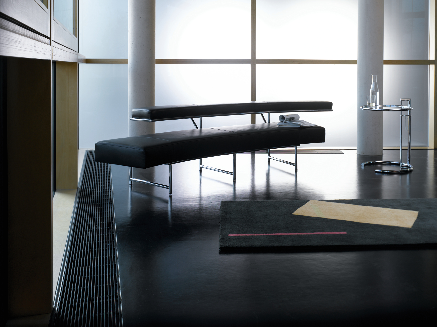 ClassiCon E1027 Adjustable Table Beistelltisch im modernen Interieur mit schwarzen Bänken und minimalistischem Design.