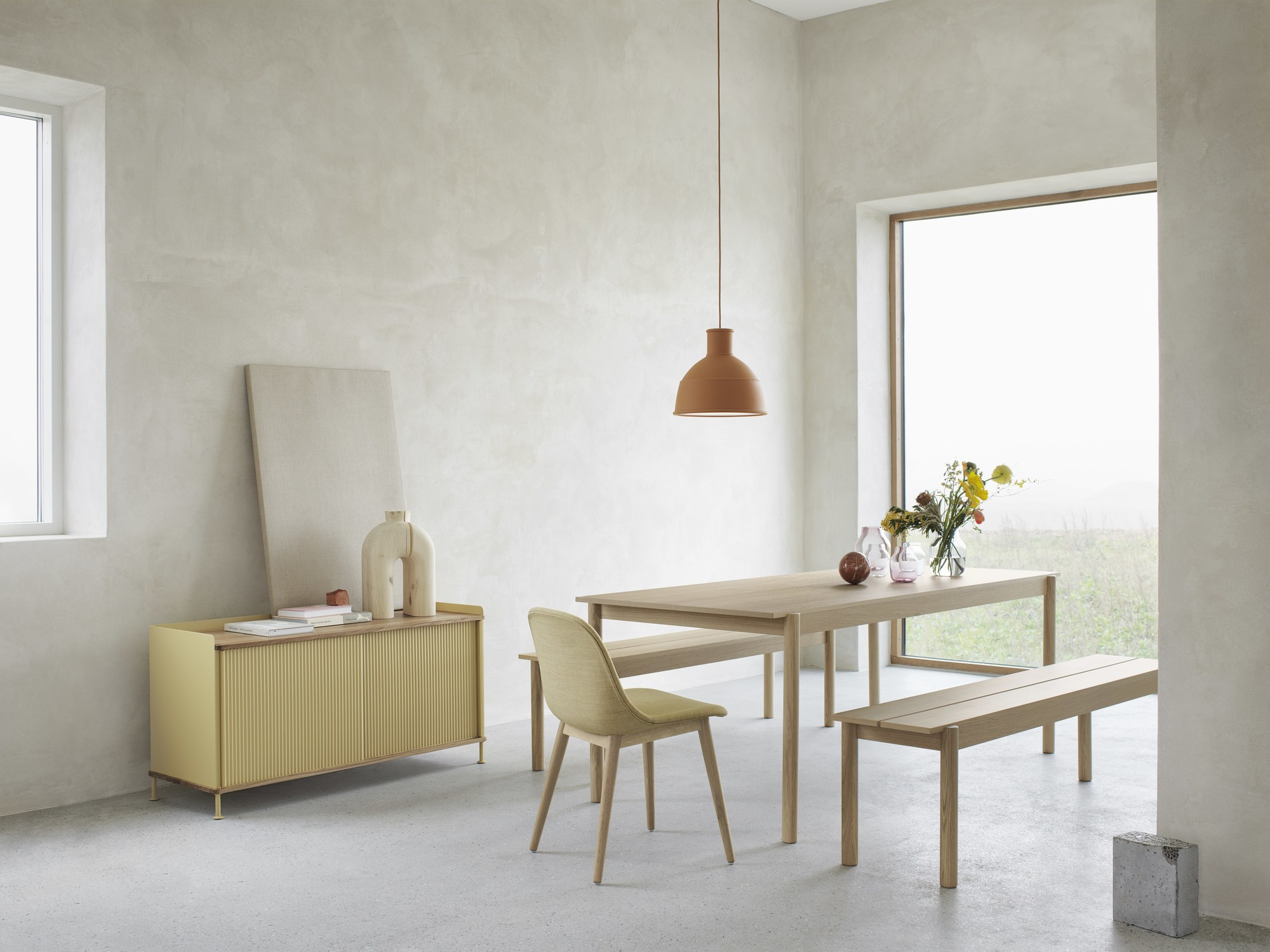 Gelbes Muuto Enfold Sideboard Low im modernen Esszimmer mit Tisch, Bank und Stuhl.
