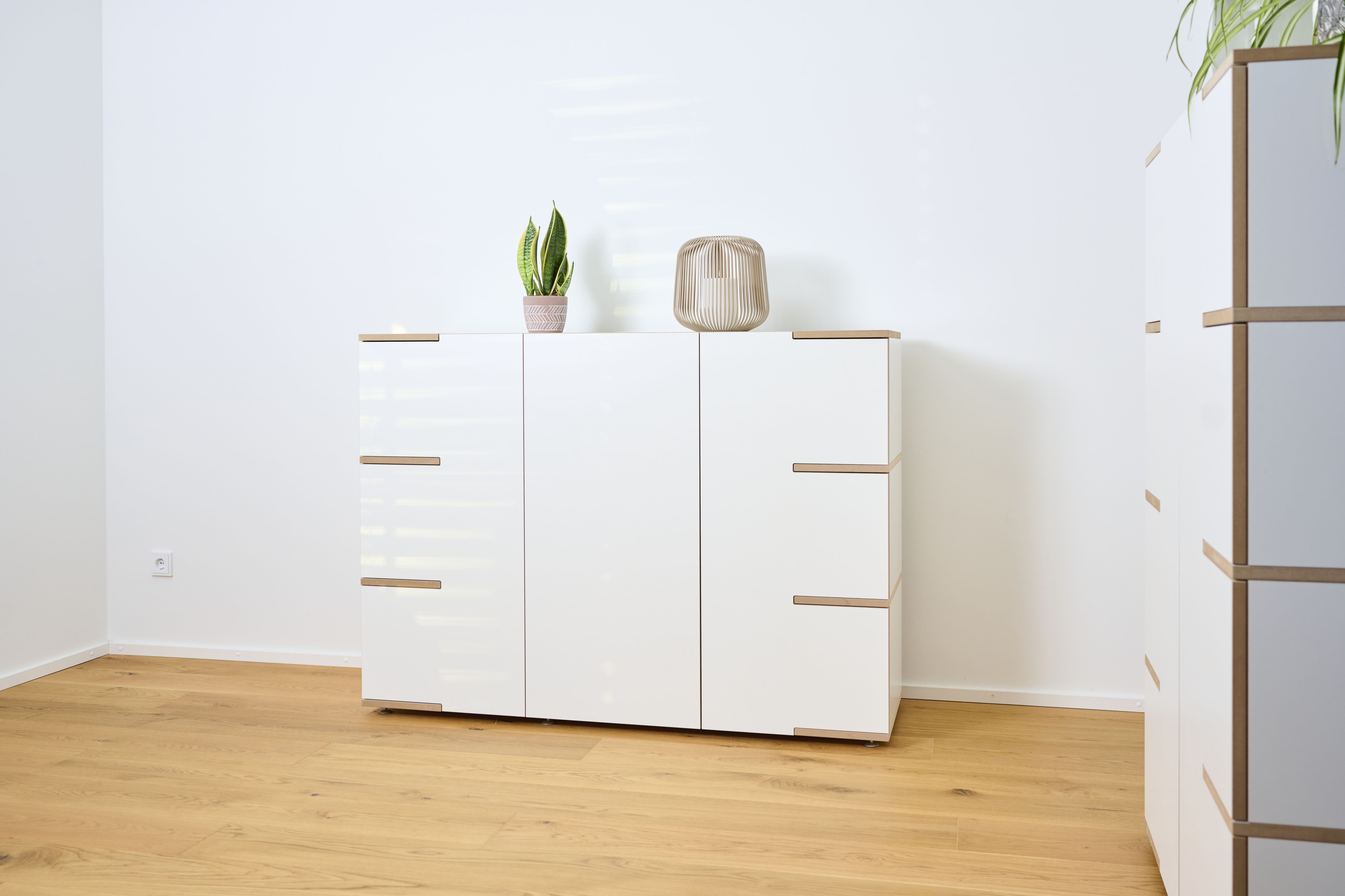 Modernes, weißes Stau Sideboard von Tojo mit Holzdetails, dekoriert mit Pflanze und Lampe.